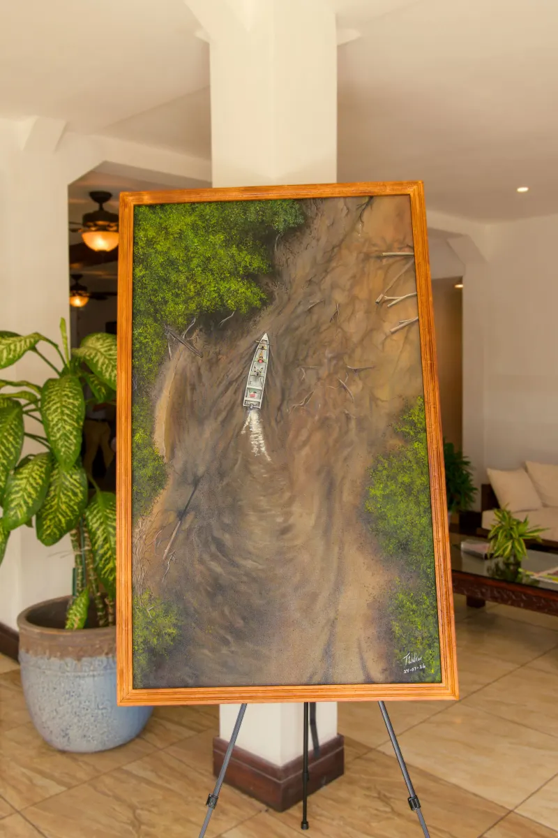 A painting of a boat on a winding forest river, seen from above, on an easel
